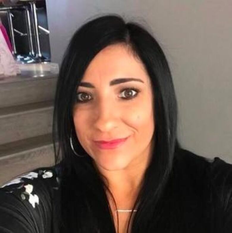 A woman with long black hair takes a selfie.