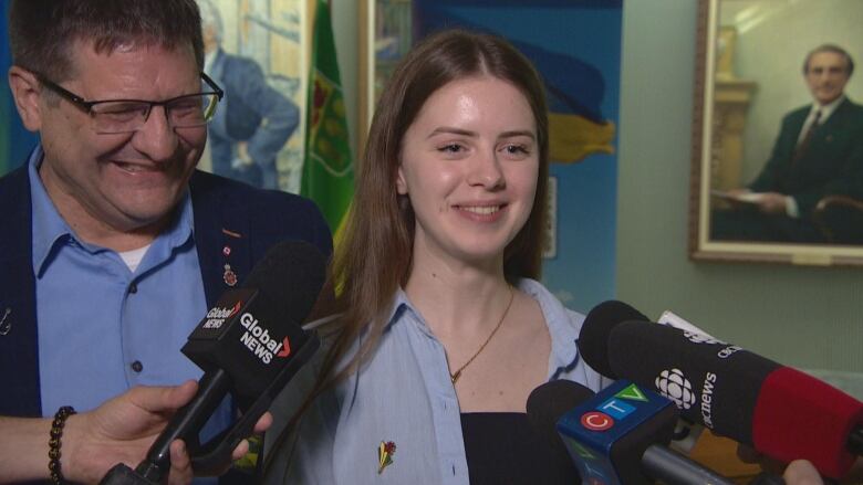 A woman can be seen smiling as reporters as her questions.