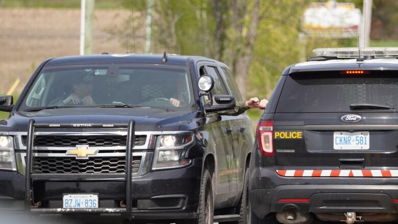 Two OPP officers greet each other between vehicles.