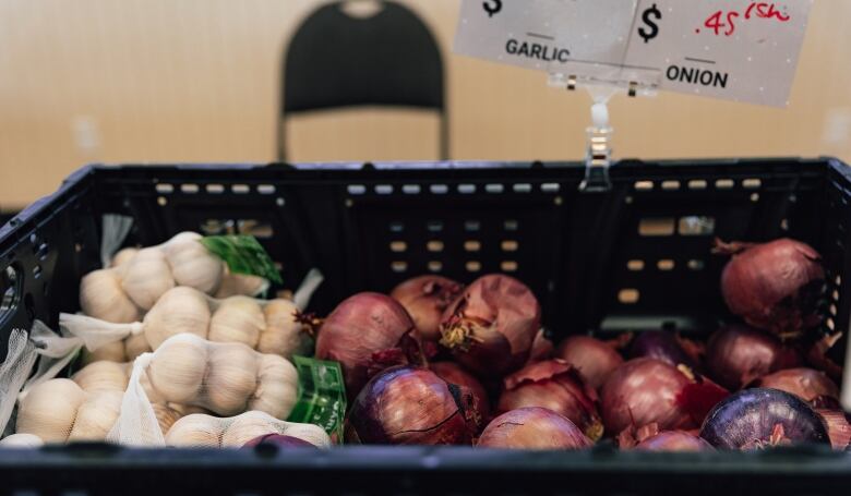 A close-up of onions and garlic bulbs at a market.