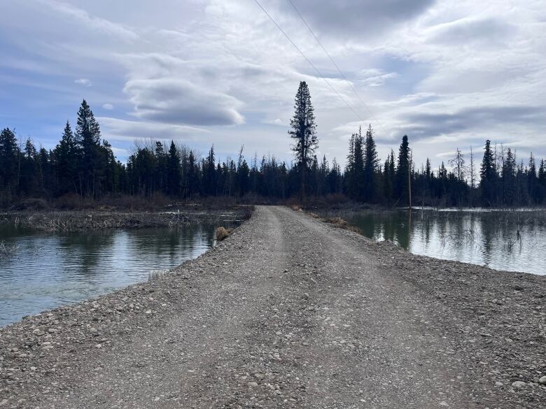 A gravel driveway with water on either side.