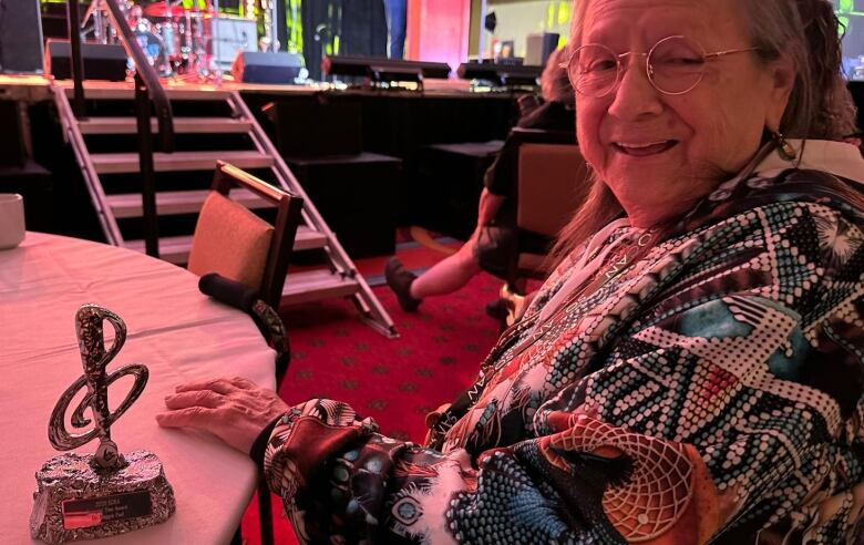 Maggie Paul sits with her award at a table.