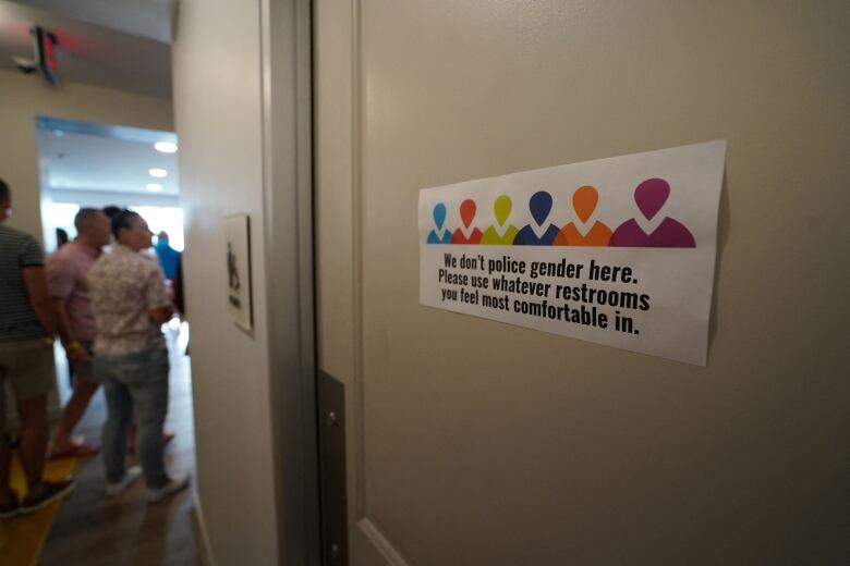 A paper sign on a door with multi-colour illustrations of people and words in black type.