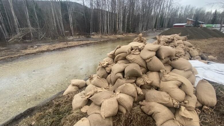 A pile of sandbags beside a flooded road