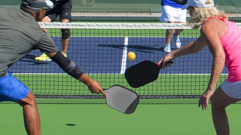 Two pairs of players play pickleball outdoors at a pickleball court.