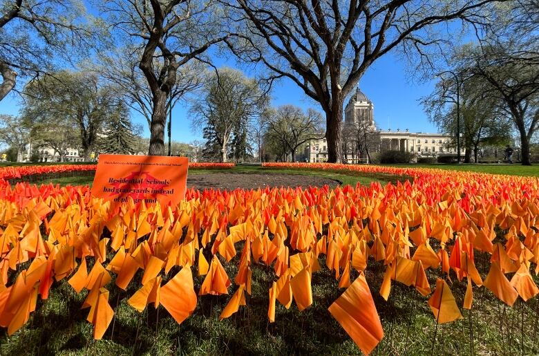 An orange sign reads 'Residential Schools had graveyards instead of playgrounds.'