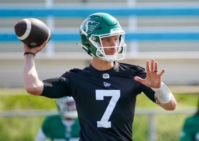 A player holds a football up, about to throw.