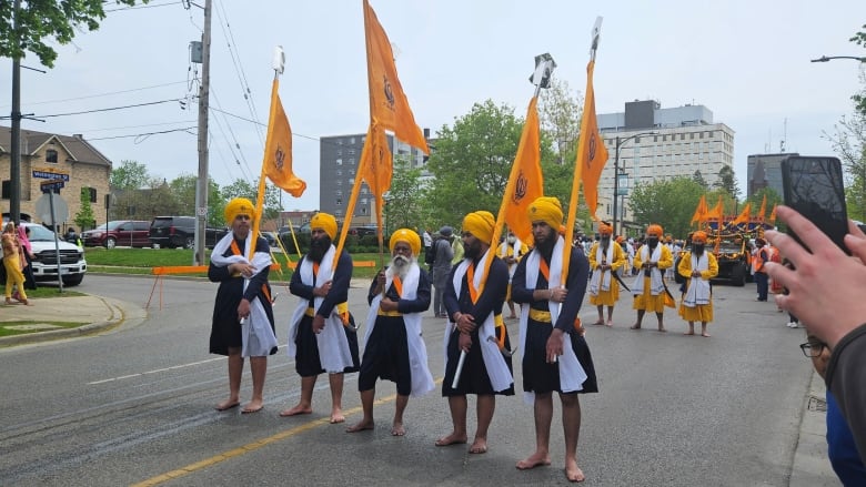 People carrying the Khalsa flag and leading the parade attended by thousands of people in Victoria Park. 