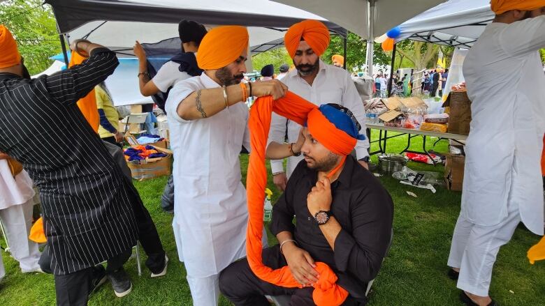 Jaspinder Gill and his team are tying a turban on an attendee. 