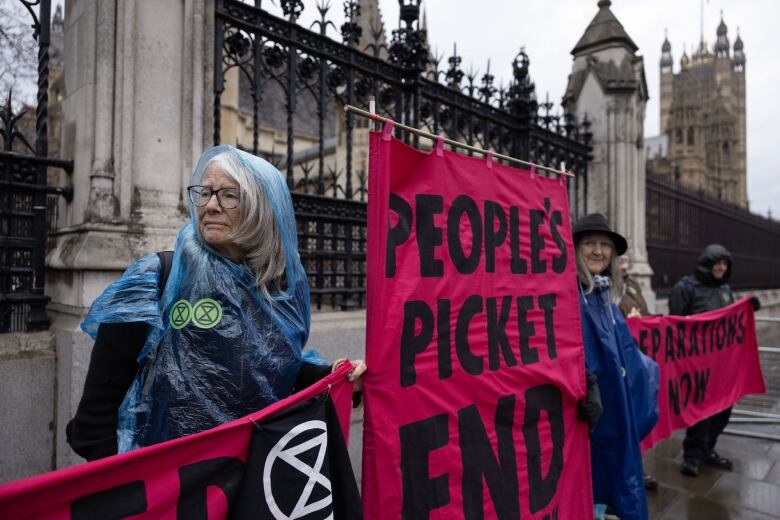 An elderly woman and other climate protesters demonstrate in the rain.