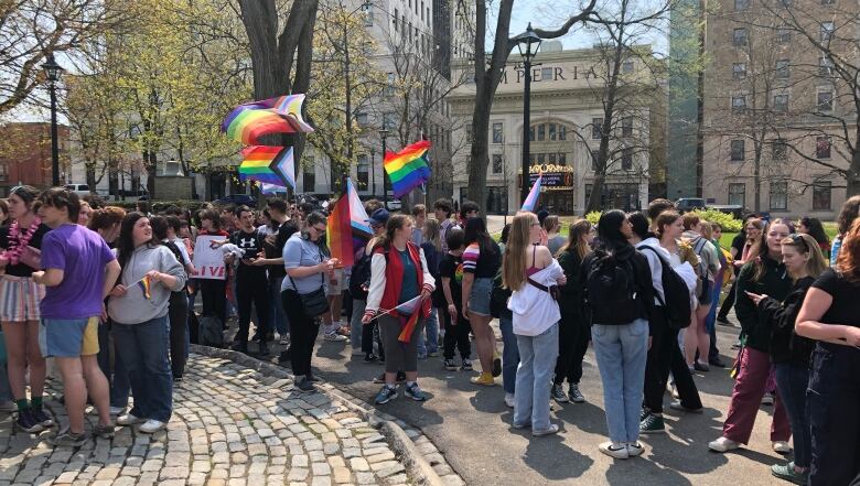 A crowd of people huddled together with some rainbow flags raised in the air.