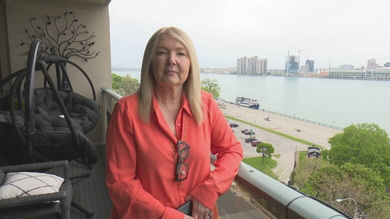 Joan Charette stands on her balcony which overlooks a parking lot on the riverfront where she says drivers of cars with loud engines keep her and her husband up at night.