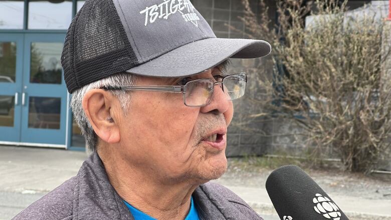 A man wearing a ball cap speaks into a microphone. 