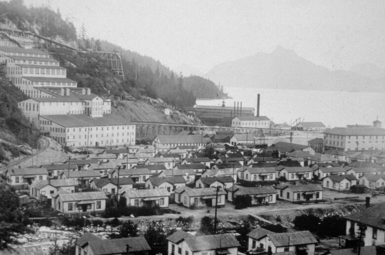 A black and white photo with dozens of bunk houses surrounding the mill. 