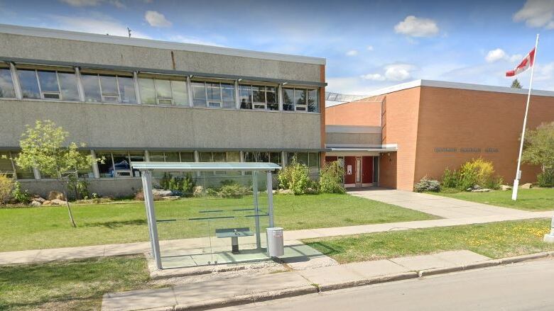 A brick and stucco two-storey school building is pictured on a summer day.