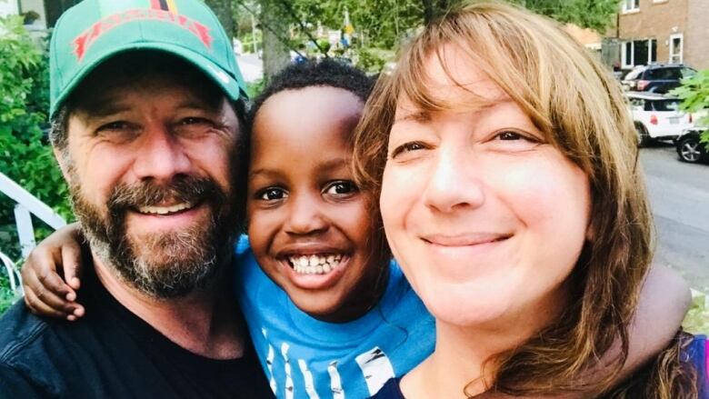 A little boy smiles in a selfie with his mother and father.