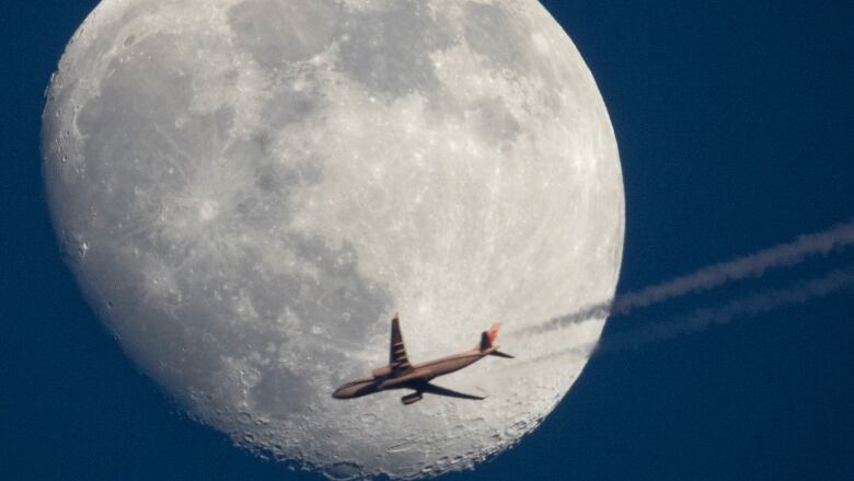 An Airbus A330 belonging to Air China is silhouetted against the moon as it flies over St. Petersburg, Russia on April 13, 2022.