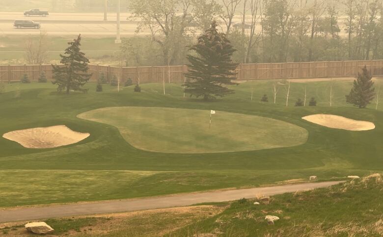 A photo shows a distant green with two bunkers on either side. 