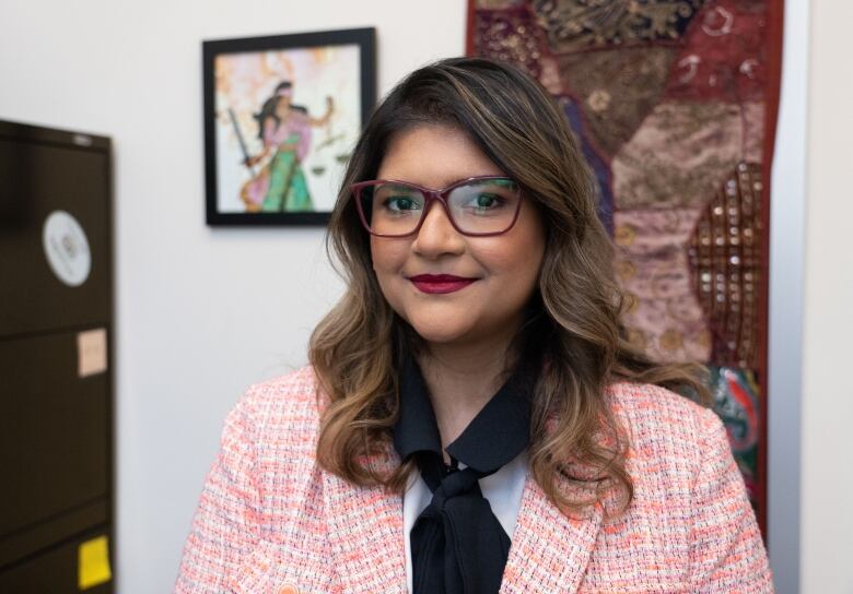 Nadia Zaman wears a pink, tweed jacket and smiles for the camera.