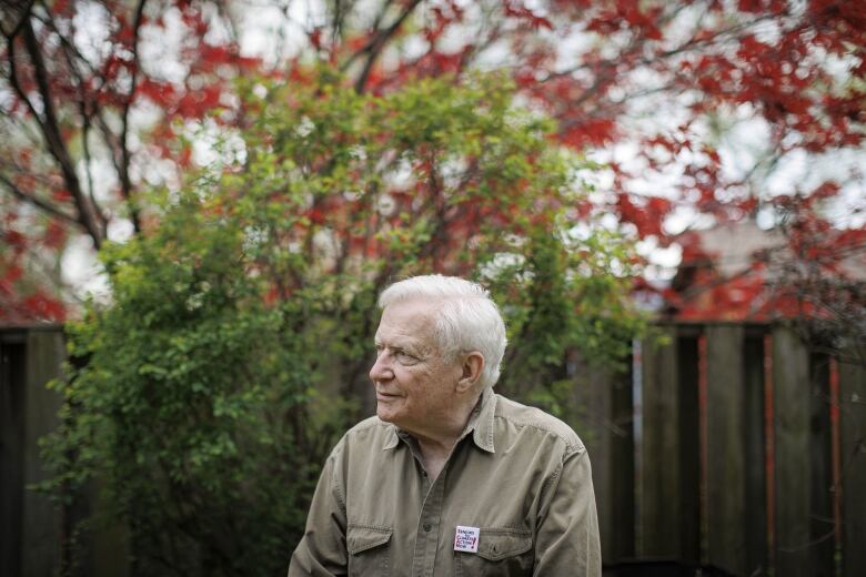 An elderly man sits in his garden.