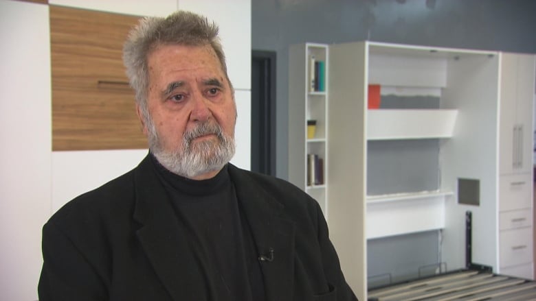 A man stands in front of a Murphy bed showroom model.