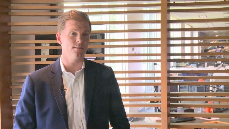 A man in a blue suit stands in the CBC Windsor studio. 