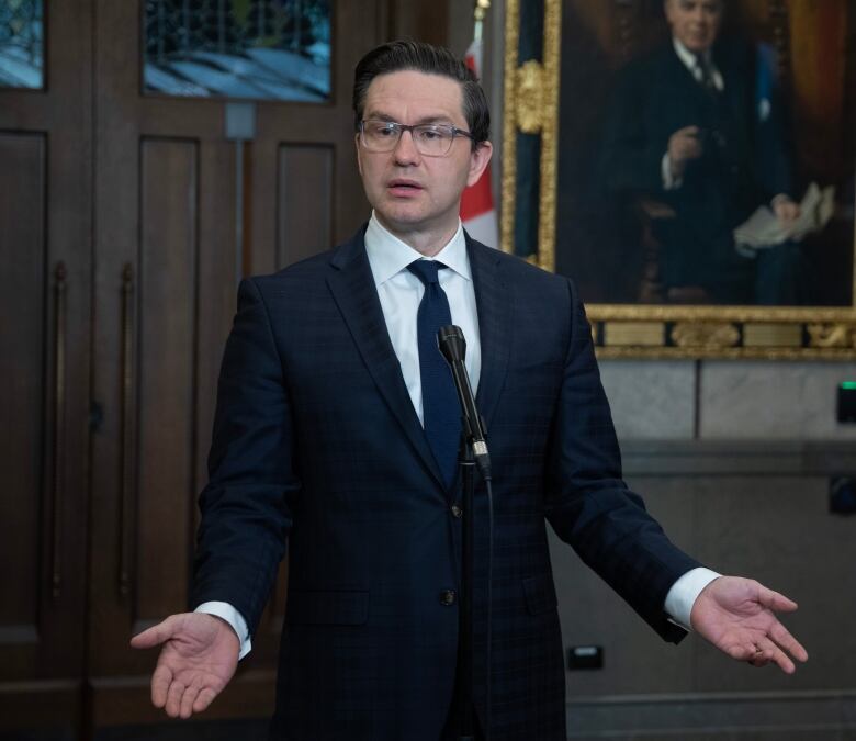 A man in a suit gestures at a podium.