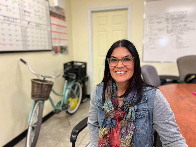 A woman smiles for a photo while sitting at a desk.