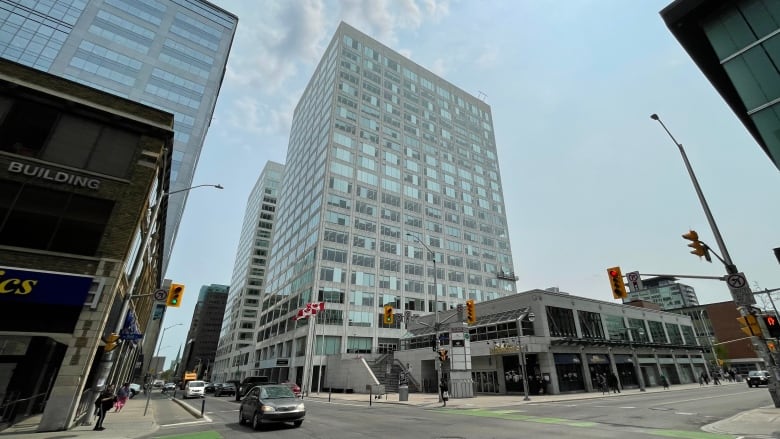 A downtown intersection with a large white and glass tower.