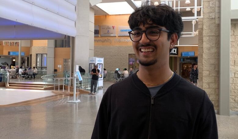 A young man smiles at the camera. 