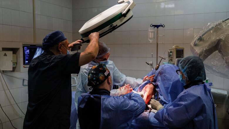 A Ukrainian surgeon and other health professionals operate on an injured soldier.