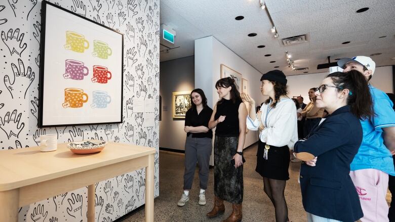 A group of people are pictured viewing artwork in a museum.