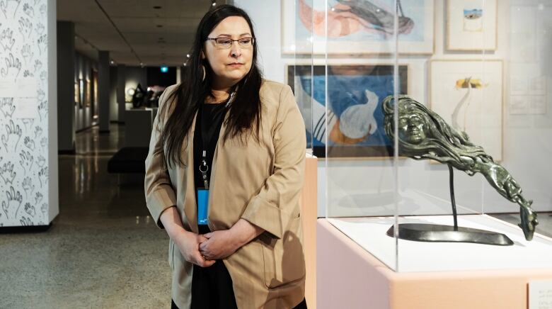 A woman is pictured in a museum, looking down toward an artwork.