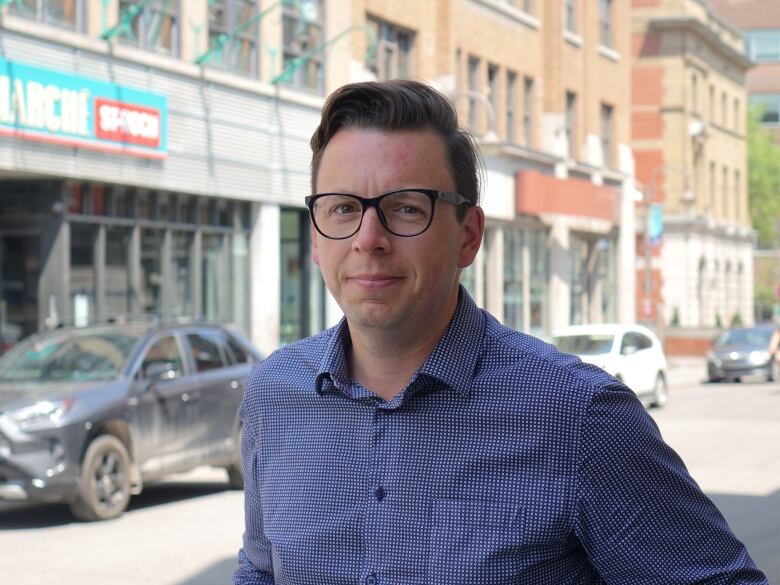 A man looks into the camera while standing outside. 