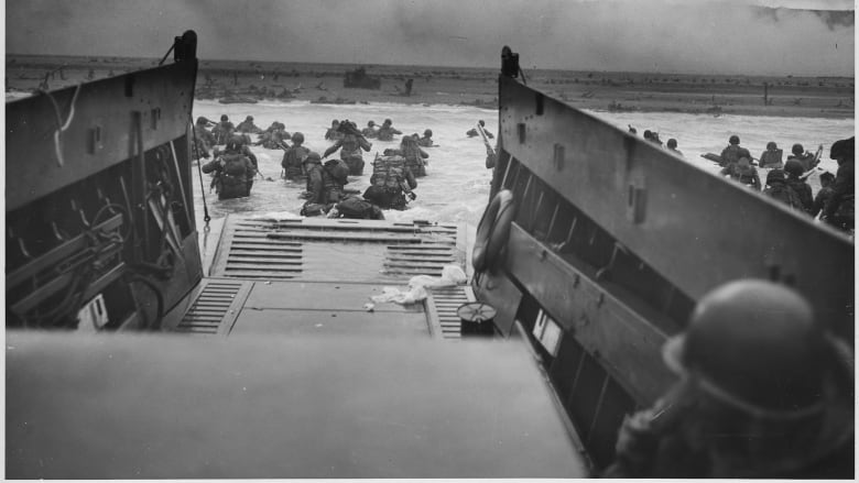 This black and white photo shows American soldiers landing at Omaha Beach in Normandy, France, on the morning of June 6, 1944, as part of the D-Day invasion.