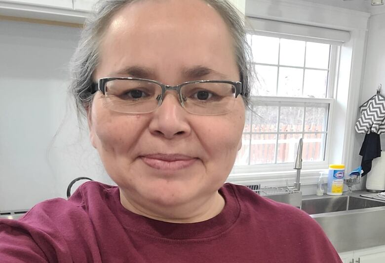 An Indigenous woman stands with a red shirt