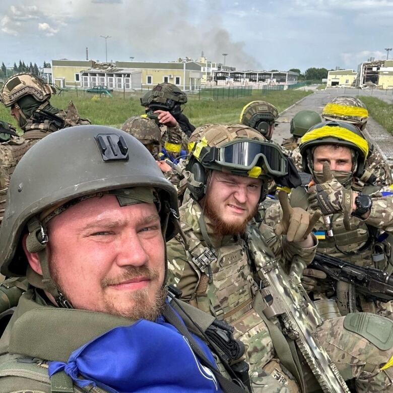 Soldiers pose for a selfie atop an armoured vehicle.