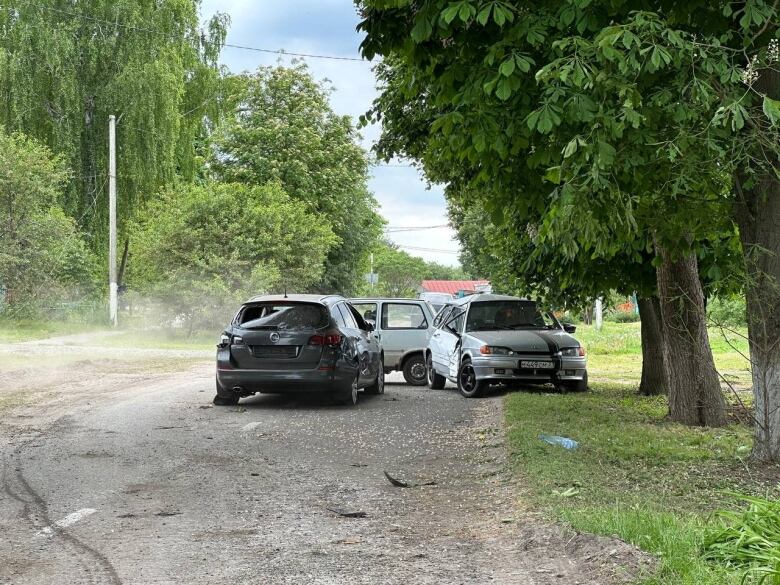 Damaged cars are seen abandoned on a road.