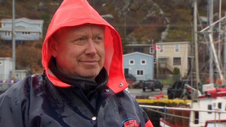 A man wearing a rain coat stands on a wharf.