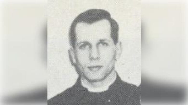 A black and white photo of a young white man with brown hair wearing a dark coloured smock.