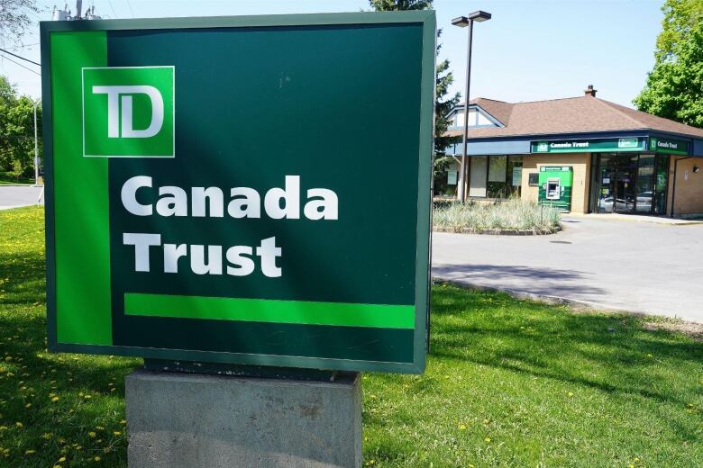 Green TD sign on lawn in front of small bank building.