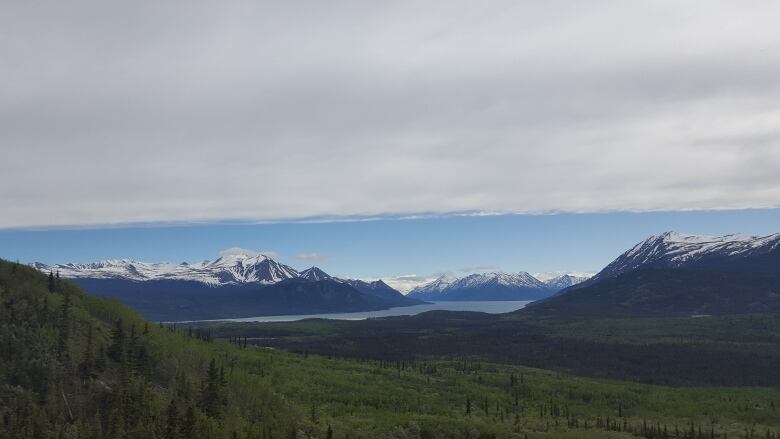 A lake is seen in the distance, surrounded by mountains.