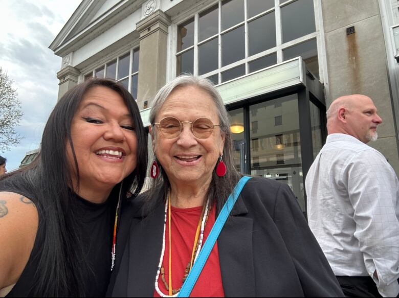 Two women stand next to each other, smiling.