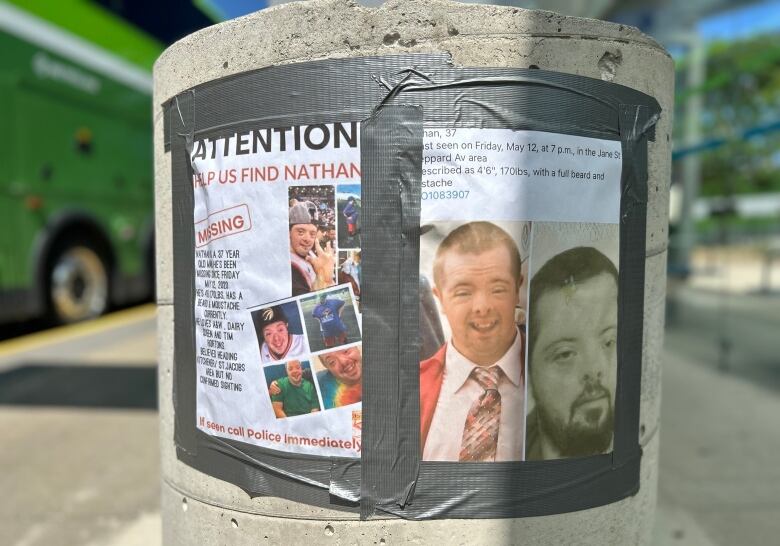 Two posters taped with duct tape to a cement pole, one has two photos of a man with Down syndrome