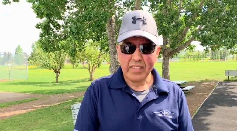 A man wearing a baseball cap smiles at the camera. 