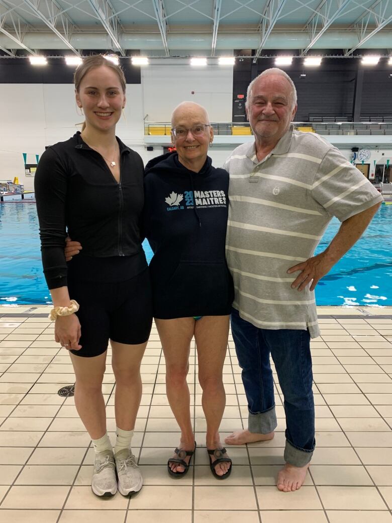 Three people stand in front of a pool.