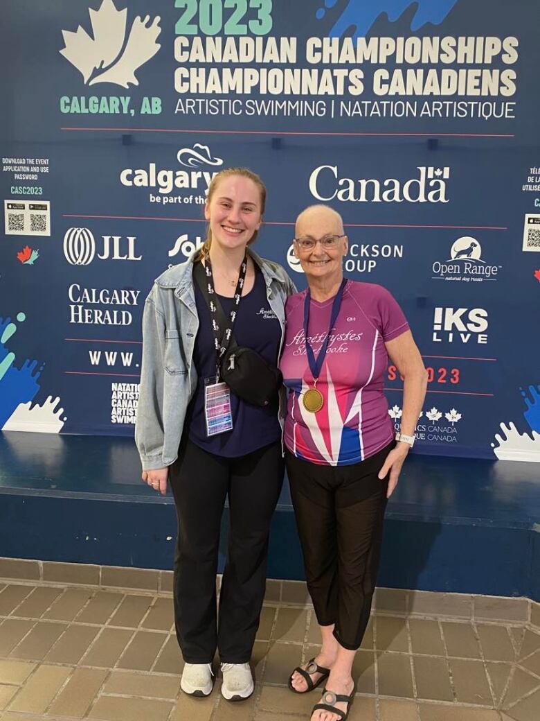 Two women pose, one with a medal.