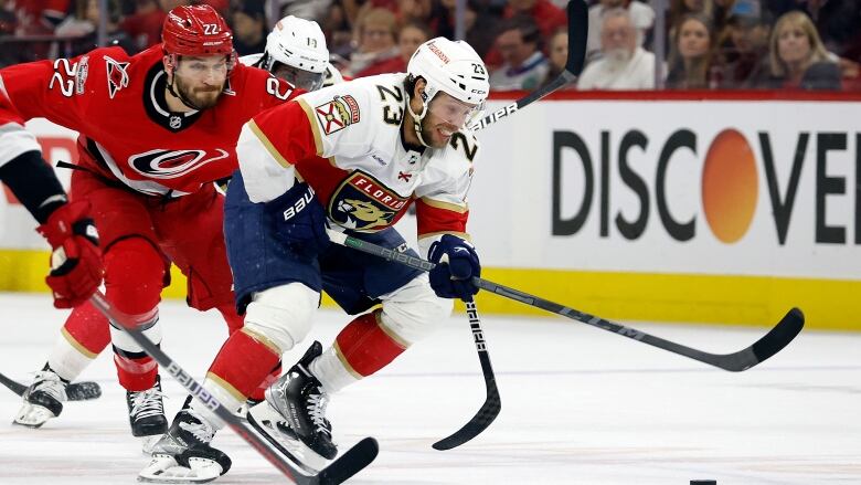 Florida Panthers' Carter Verhaeghe (23) skates the puck away from Carolina Hurricanes' Brett Pesce (22) during the first period of Game 2 of the NHL hockey Stanley Cup Eastern Conference finals in Raleigh, N.C., Saturday, May 20, 2023. 