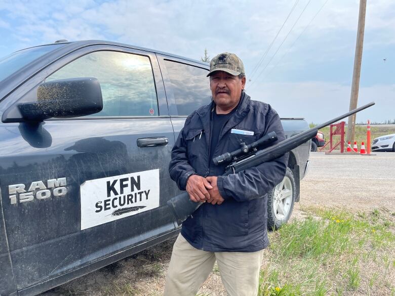 A man holding a gun next to a truck.