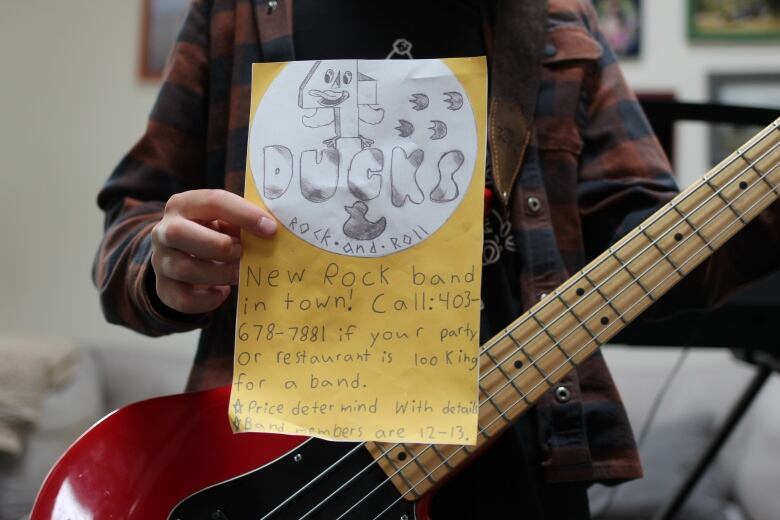 A band member holds a yellow poster featuring the Four Ducks' logo.